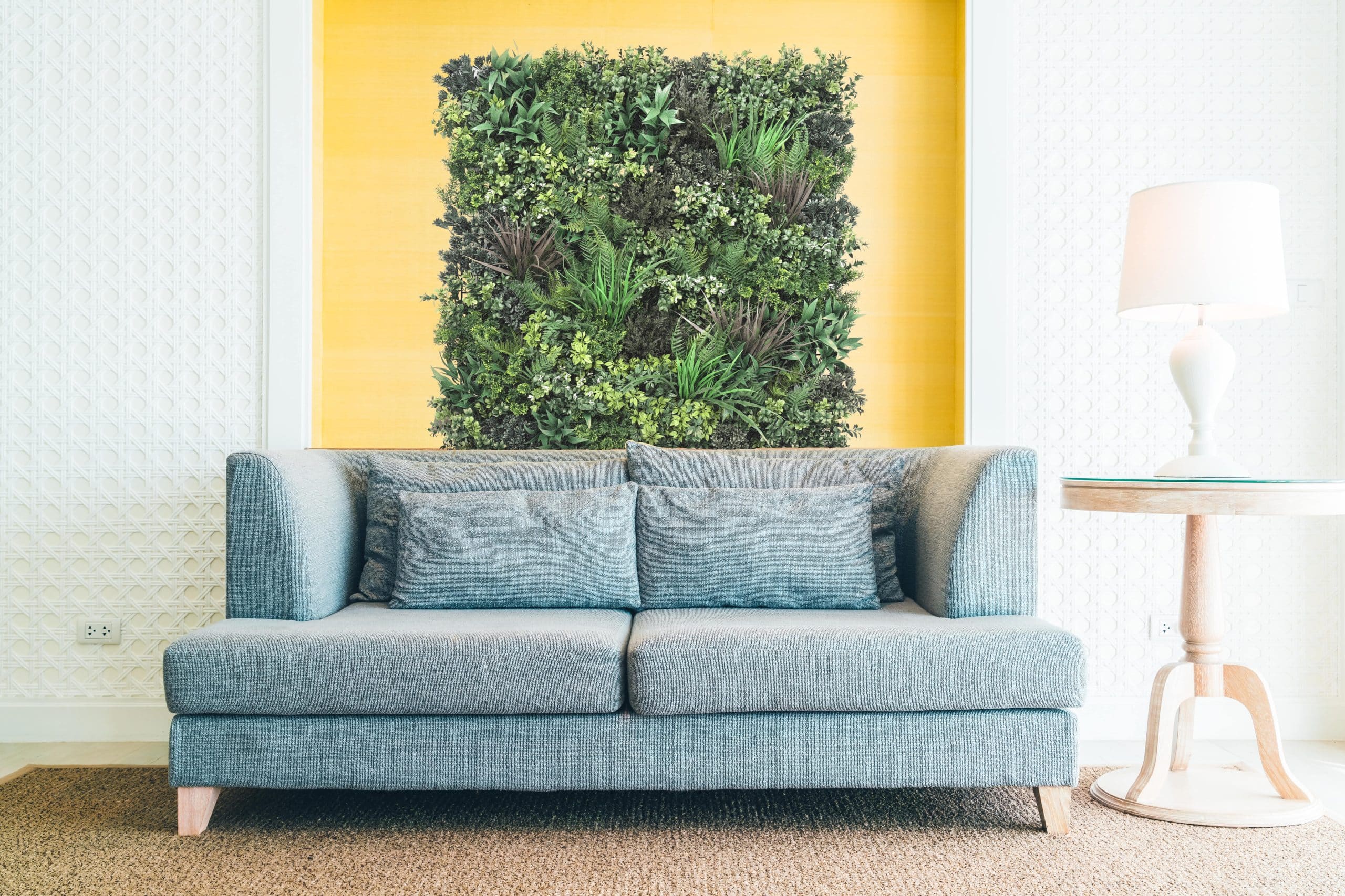 Sala moderna con sofá azul frente a jardín vertical de césped artificial decorativo